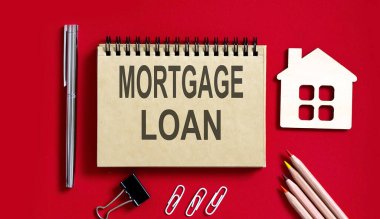 MortGage kredi metni, kalemler, ofis aletleri ve model ahşap evle birlikte deftere yazılmış.