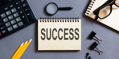 Ofis araçları ile gri bir arkaplan üzerinde SUCCESS yazıları olan bir not. iş