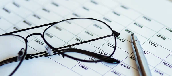 Financial papers with graph and charts ,pen and glasses on the table