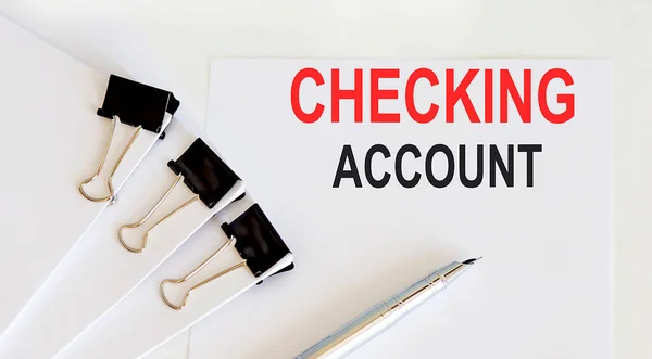CHECKING ACCOUNT written on white page with office tools