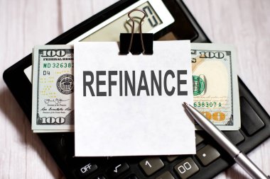 Hesap makinesinde dolar ve kalem ile metin REFINANCE beyaz kağıt