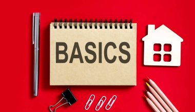 Not defterine kalemler, ofis aletleri ve model ahşap evle yazılmış BASICS metni