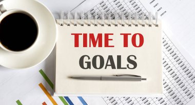 Text TIME TO GOALS on the notepad with office tools, pen on financial report