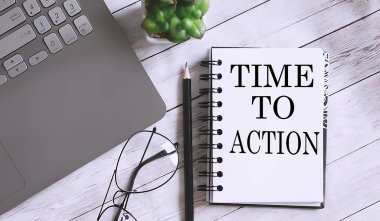 Time to Action kelimeleriyle dolu bir defter ofis aletleri, beyaz masada dizüstü bilgisayar. iş