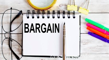 BARGAIN ofis araçları ile beyaz arkaplan üzerine not defteri ile yazılmış