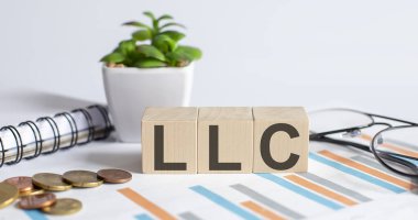 LLC konsepti tahta küpler ve çiçek, bardaklar, grafikteki madeni paralar üzerine