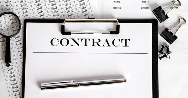 White sheet with the text of the CONTRACT on background of documents and graphs.
