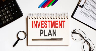 Not defterine kalem ve ofis araçlarıyla yazılmış INVESTMENT PLAN metni