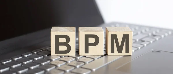 BPM Business Process Management written on a wooden cube on the laptop