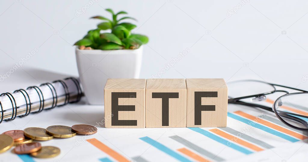 ETF word on wood blocks concept with chart, coins, notebook , glasses.