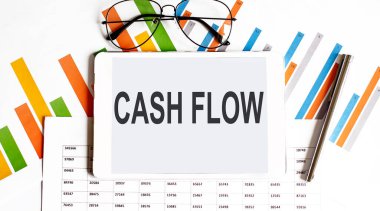 İş grafiklerinde, bardaklarda ve kalemlerde Cash Flow yazan tablet