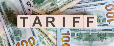 TARIFF 'in ahşap bloklardaki kavramsal sözcükleri dolar banknotlarından güzel bir arka planda. İş dünyası