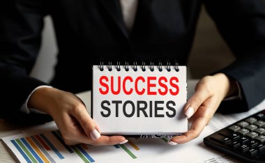 Bir iş kadını, elinde SUCCESS STORIES ile bir not ebppk tutuyor.,