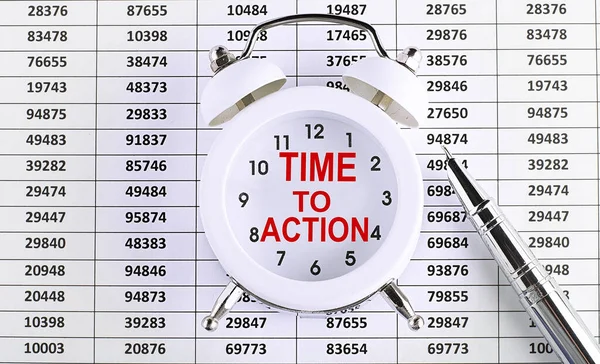 Business concept. text TIME TO ACTION on alarm clock on the chart background