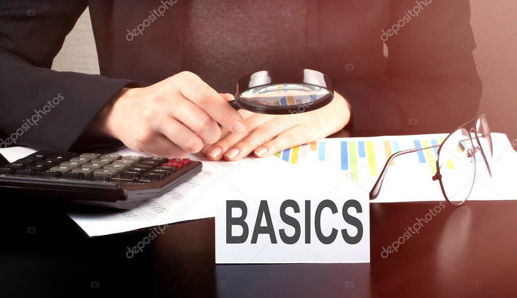 Close up Business woman using calculator and charts do math finance on the wooden desk office and business working background with text BASICS