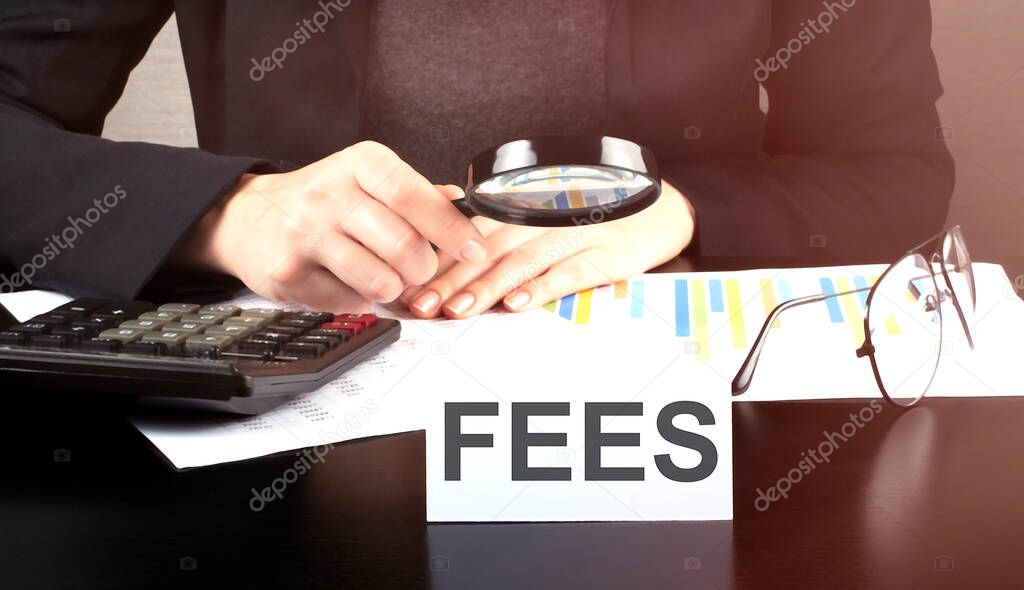 Close up Business woman using calculator and charts do math finance on the wooden desk office and business working background with text FEES