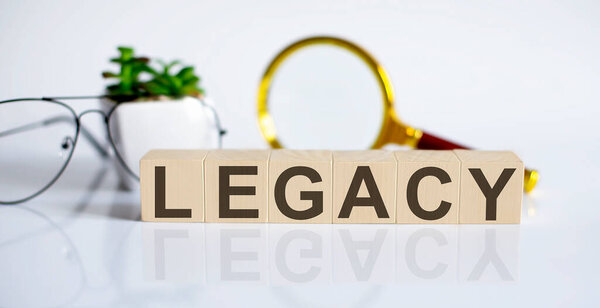 LEGACY concept on wooden cubes and flower, glasses, coins and magnifier on twhite background