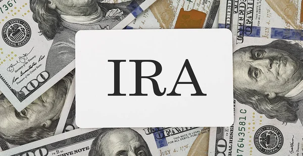 text IRA on dollars background, business concept