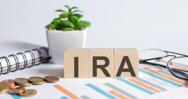 IRA sözcüğü ağaç blokları kavramı üzerine grafikler, madeni paralar, not defterleri ve camlarla. İş dünyası.