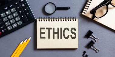 Ofis araçları ile gri bir arkaplan üzerinde ETHICS yazıları olan bir not. iş
