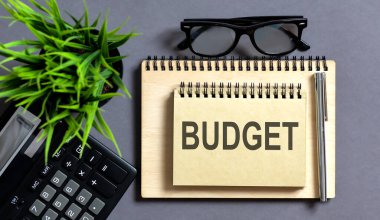 Gri tabloda metin bütçe ve hesap makinesi olan defter,