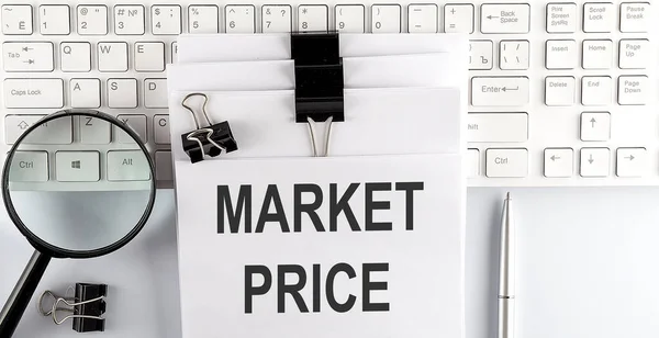 Words Market Price written on papers on computer keyboard with magnifier and pen