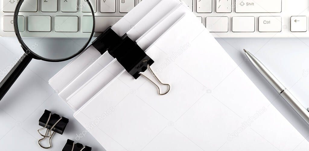 White office desk table with blank sheet, keyboard,magnifier top view