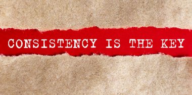 Consistency is The Key appearing behind torn paper on the red background clipart
