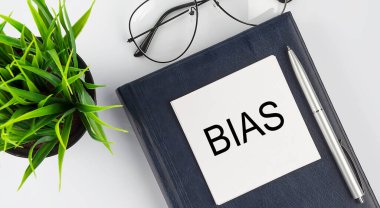 Not defterindeki etiketler beyaz arkaplanda kalem ve gözlüklerle BIAS metni