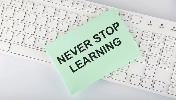 text Never stop learning on envelope on keyboard on white background