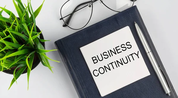 Not defteri metnindeki çıkartmalar beyaz arkaplanda kalem ve gözlüklü BUSINESS Devam Ediyor