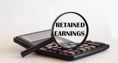 Retained Earnings konseptine odaklanmış. Hesap makinesinde metin olan büyüteç. İş dünyası