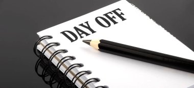Day Off siyah arkaplan üzerine küçük bir defterde yazılmış metin