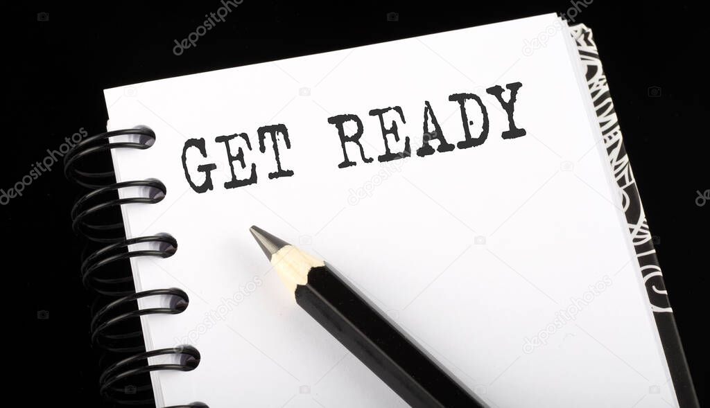 GET READY written text in small notebook on a black background
