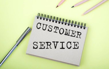 Sarı arkaplanda kalemle defterde Müşteri Hizmetleri metni