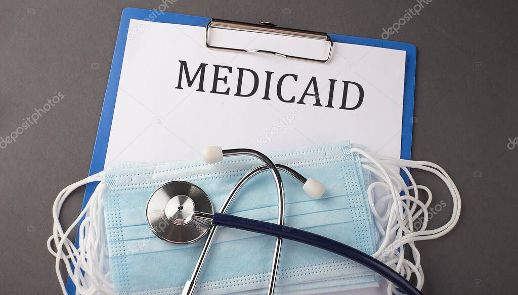 Folder with paper text MEDICAID , on a table with a stethoscope and medical masks, medical