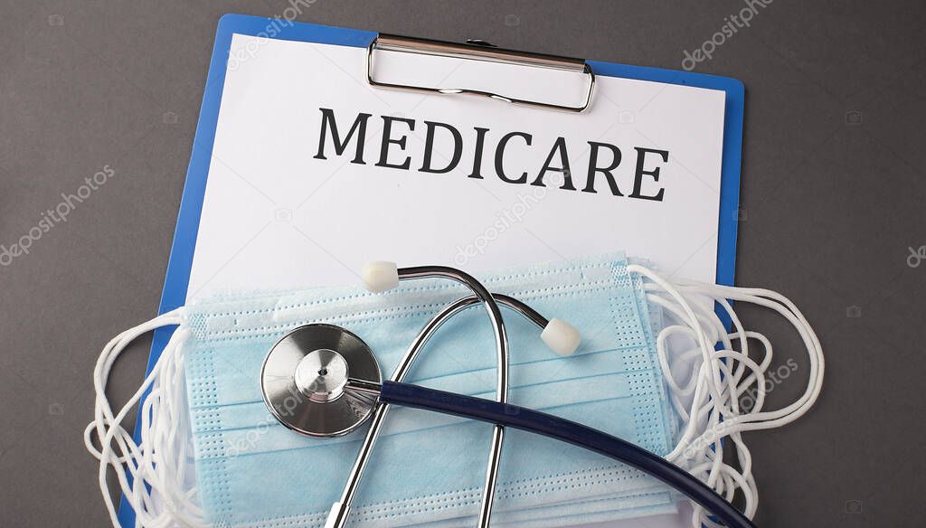 Folder with paper text MEDICARE , on a table with a stethoscope and medical masks, medical
