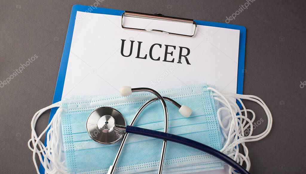 Folder with paper text ULCER , on a table with a stethoscope and medical masks, medical