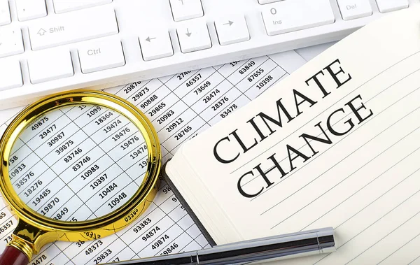 Climate Change text on the notebook with chart, magnifier,keyboard and pen