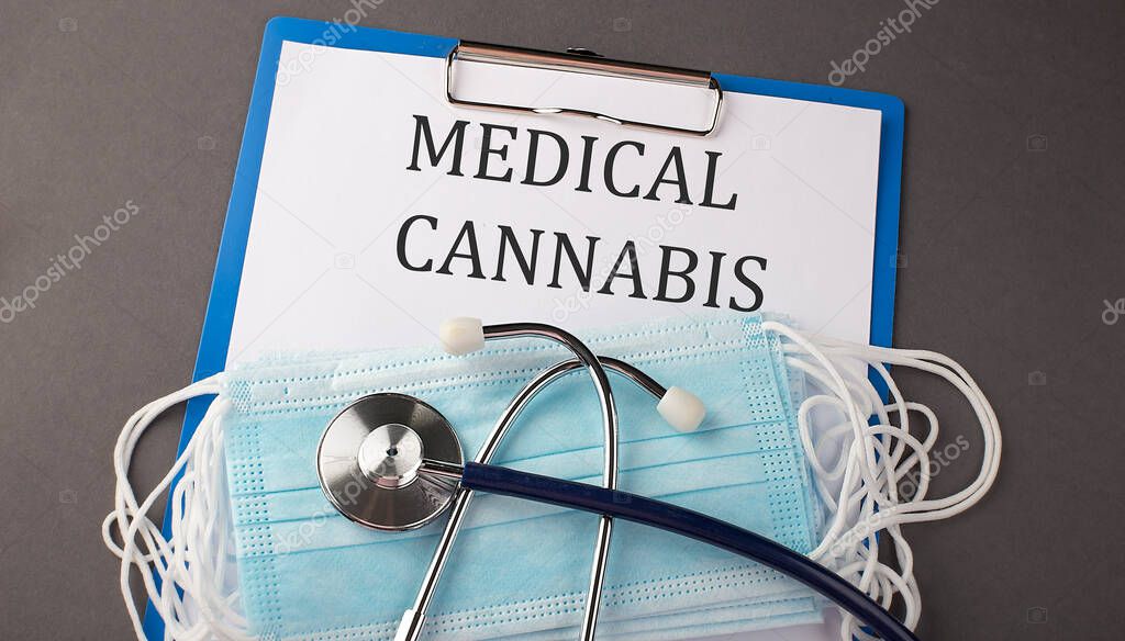 Folder with paper text MEDICAL CANNABIS , on a table with a stethoscope and medical masks, medical