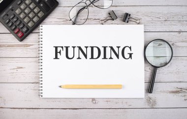 Hesap makinesi ve ofis araçları ile beyaz arkaplan üzerinde metin FUNDING ile boş defter.