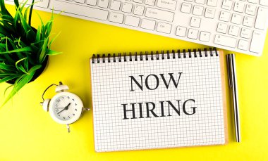 Şimdi dizüstü bilgisayarda sarı zemin üzerinde klavye, kalem ve alarm saati olan metin kiralama