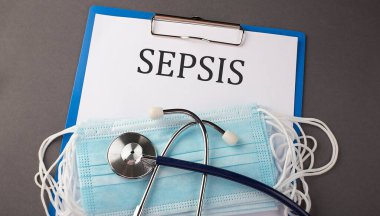 Kağıt metin SEPSIS 'i olan dizin, steteskop ve tıbbi maskeli bir masanın üzerinde, tıbbi
