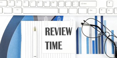 Klavyesi, çizelgesi, gözlüğü ve kalemi olan bir ofis masası. İnceleme için Time ile üst görünüm