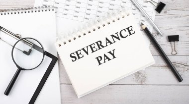 Masaüstünde kalem, ofis araçları ve grafikler ile SEVERANCE Ödeme metin notları.