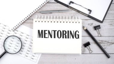 Masaüstünde kalem, ofis araçları ve grafikler ile metin MENTORING ile not.