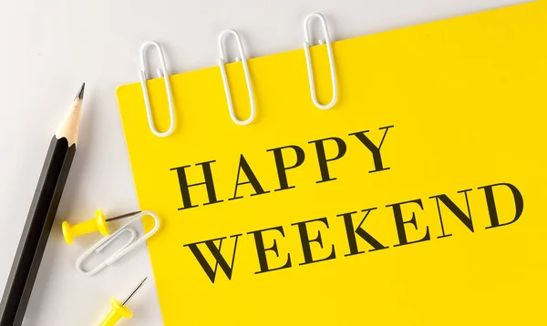 HAPPY WEEKEND word on the yellow paper with office tools on white background