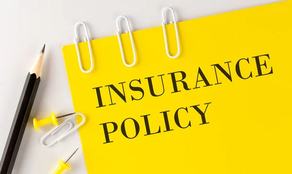 INSURANCE POLICY word on the yellow paper with office tools on the white background