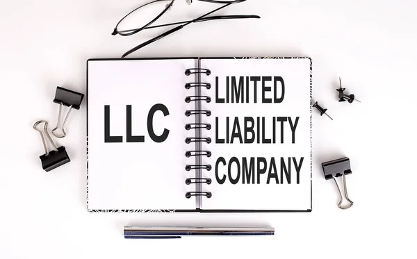 LLC Sınırlı Sorumluluk Şirketi 'nin olduğu defter ofis araçlarıyla masada.