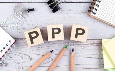 Ahşap bloktaki PPP metni ve ahşap arkaplanda ofis araçları
